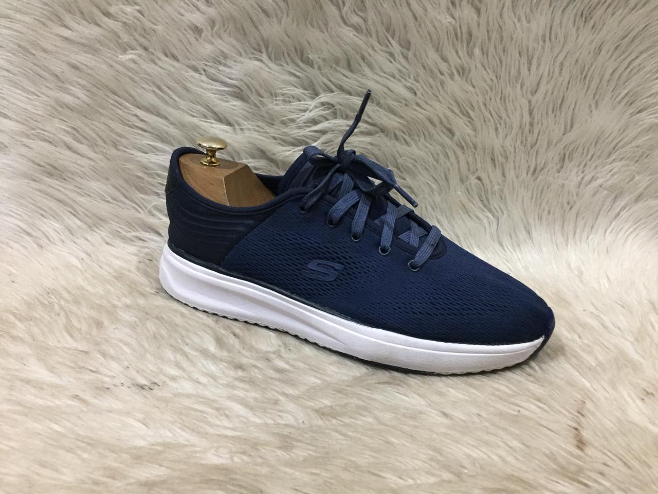 Navy blue sneaker with white sole on a fur surface