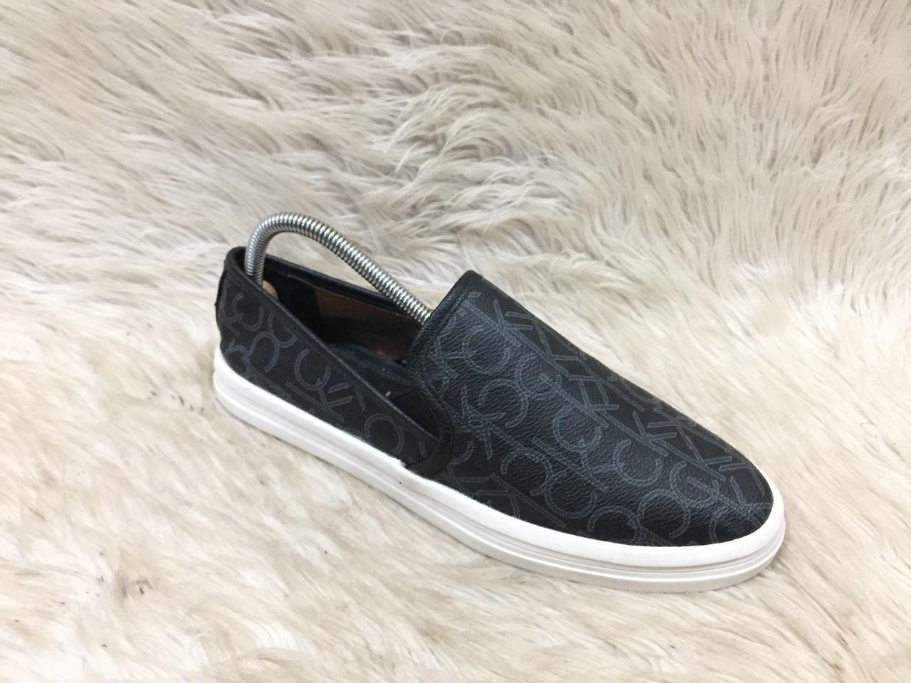 Black slip-on sneaker with white sole on a fluffy white surface