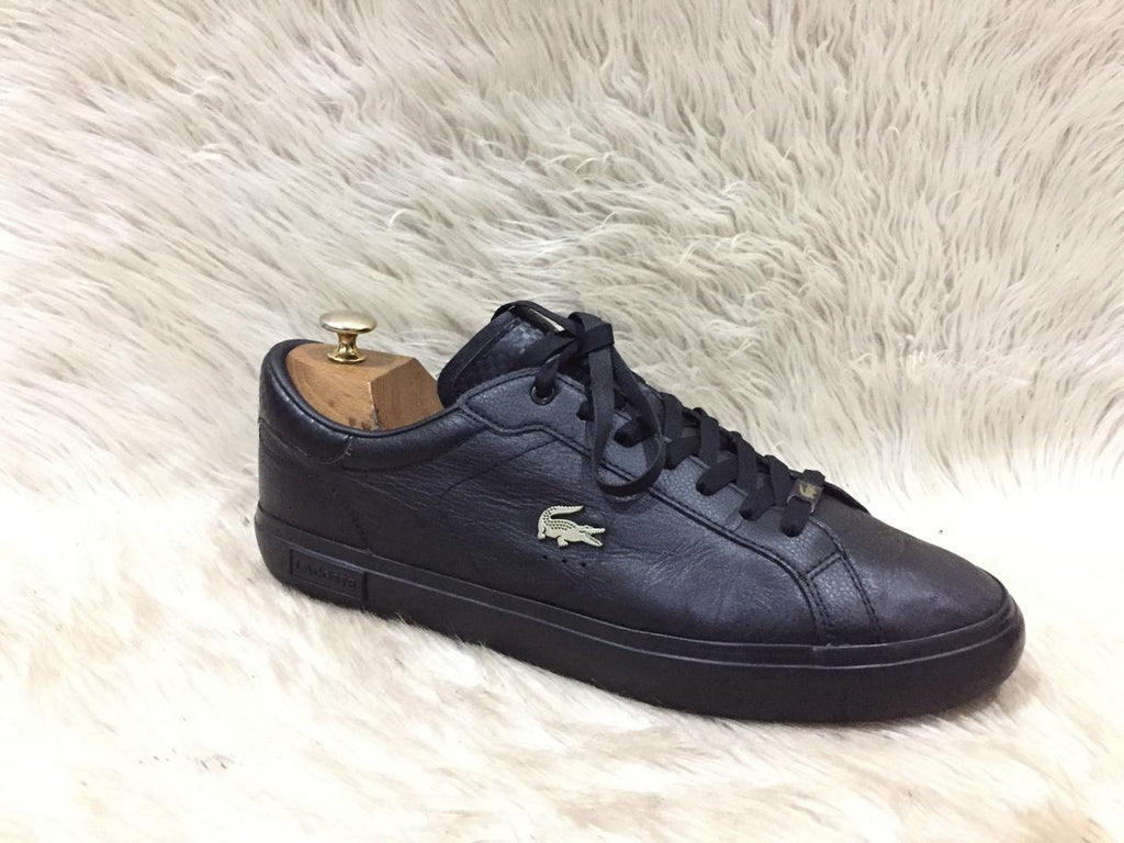 Black sneaker with brand logo on a white fur background