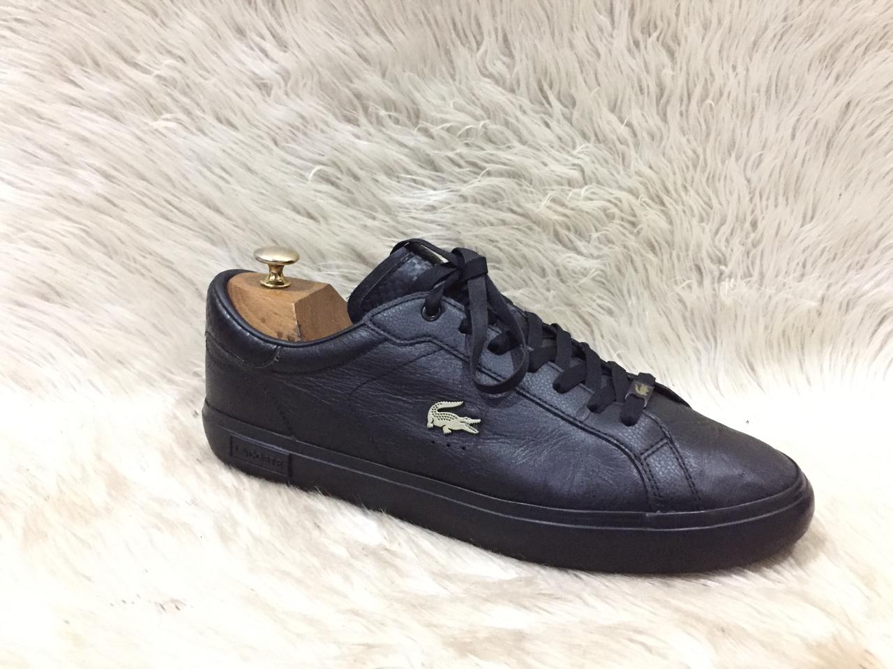 Black sneaker with brand logo on a white fur background