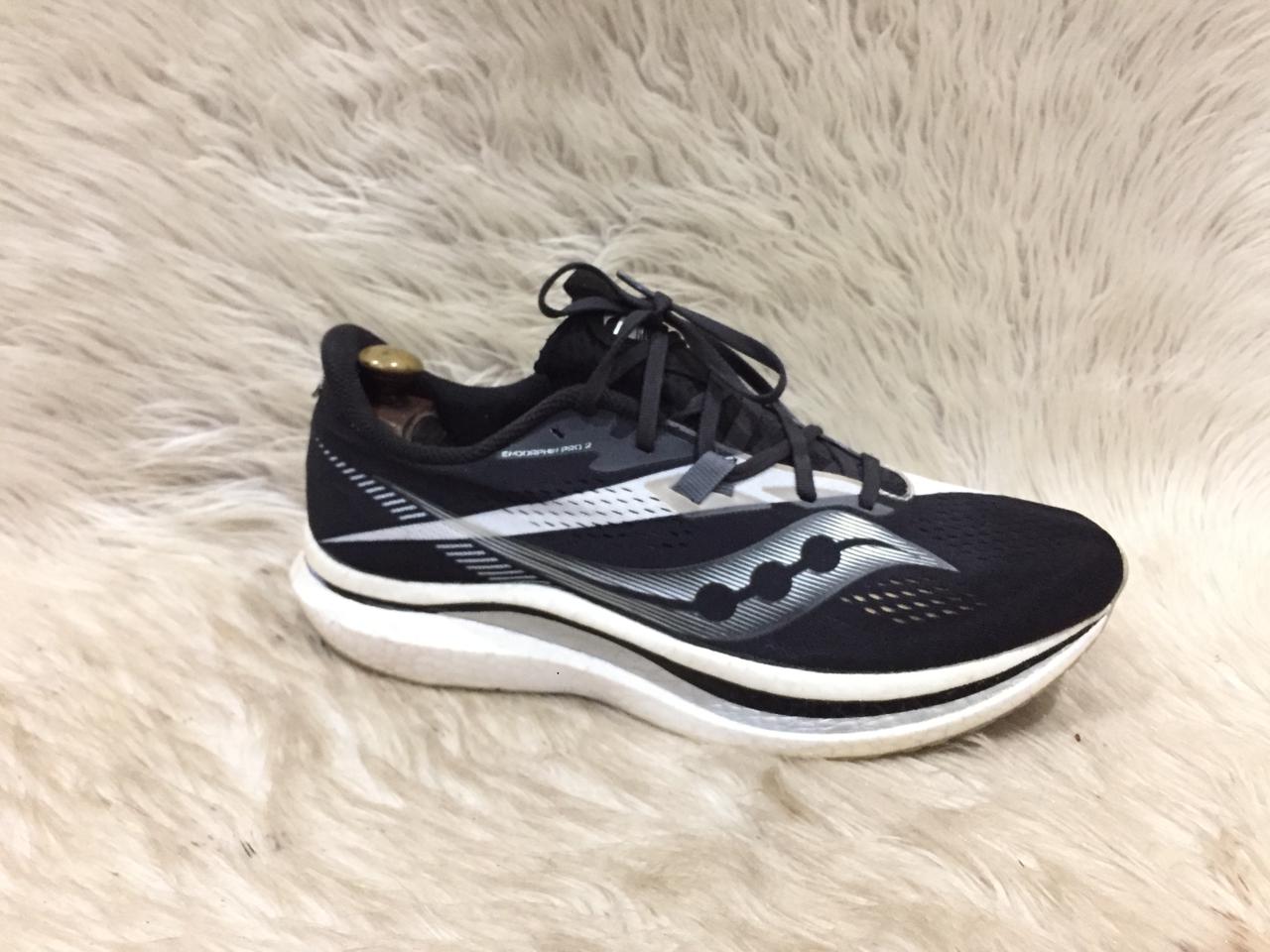 Black and white running shoe on a light fur surface