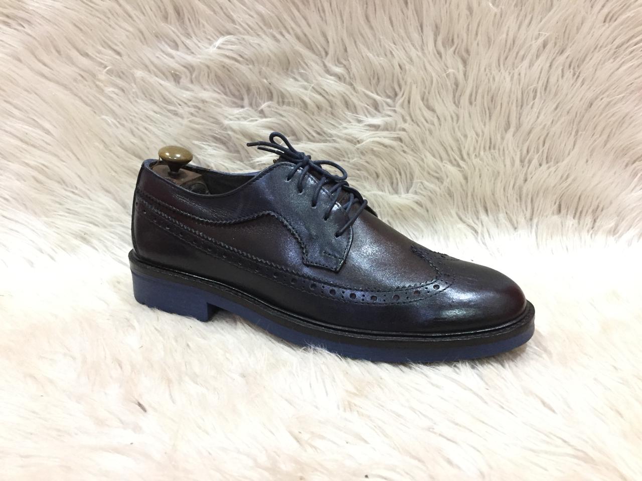 Black leather shoe on a light fur surface